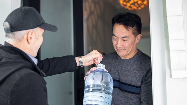 A man giving his neighbour a large bottle of water